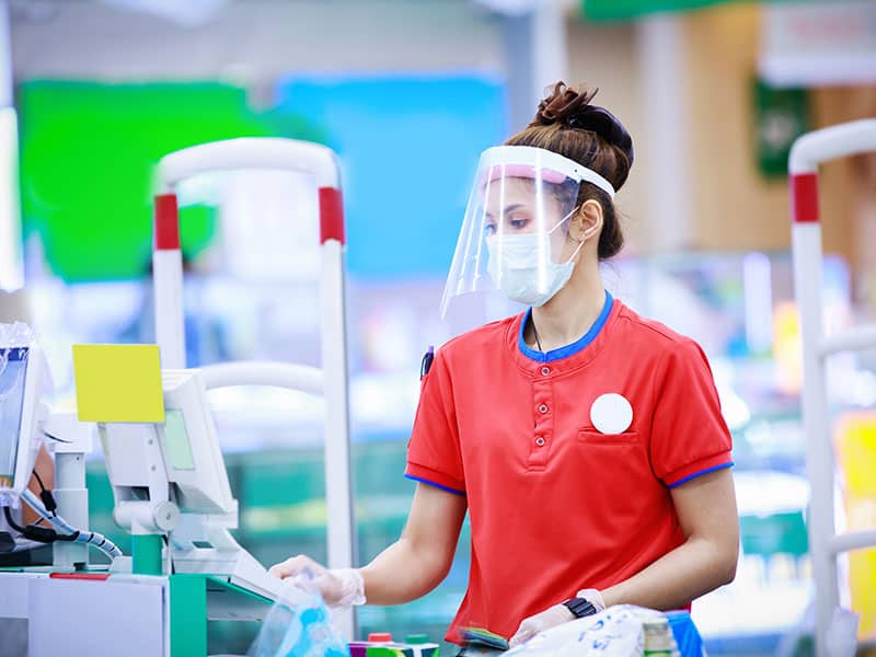 cashier with covid face shield and mask